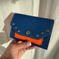 PORTE MONNAIE BLEU/ORANGE CLOUTÉ